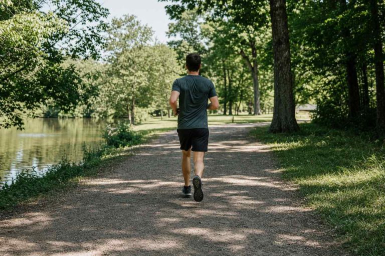 A runner in athletic running shorts jogging on a sunny park trail