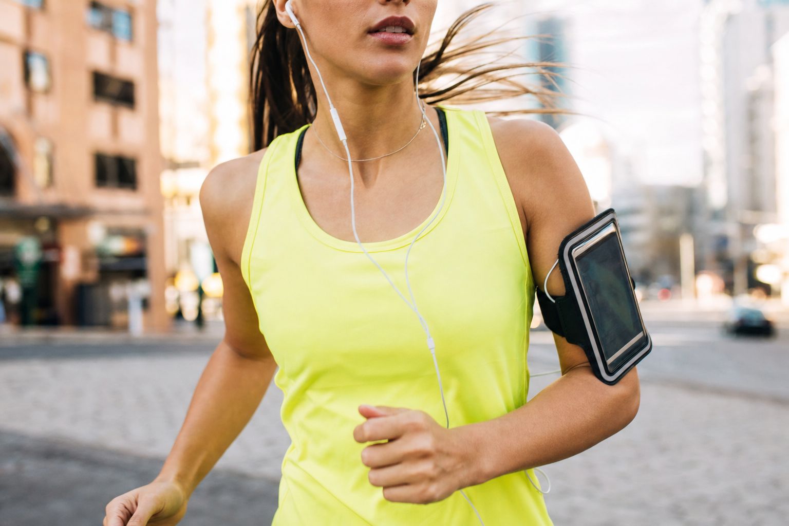 A phone armband on a runner's upper arm on a city street, phone screen facing out