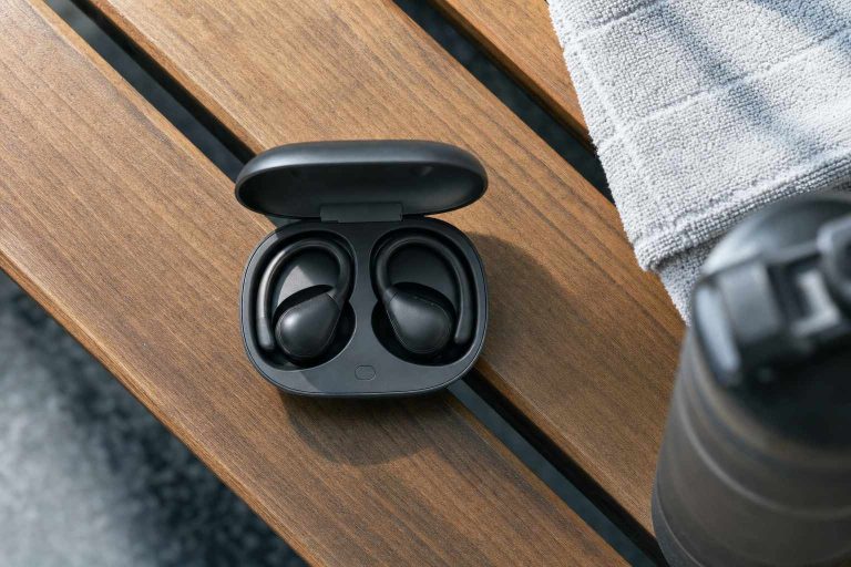 Wireless workout earbuds in an open charging case resting on a gym bench