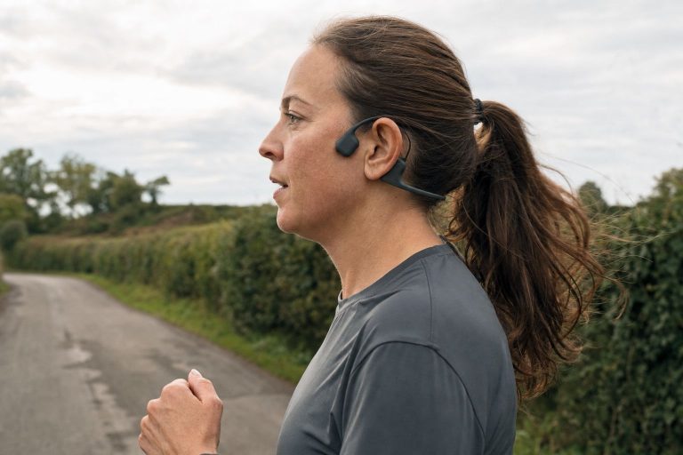 A runner wearing bone conduction headphones that sit in front of the ear