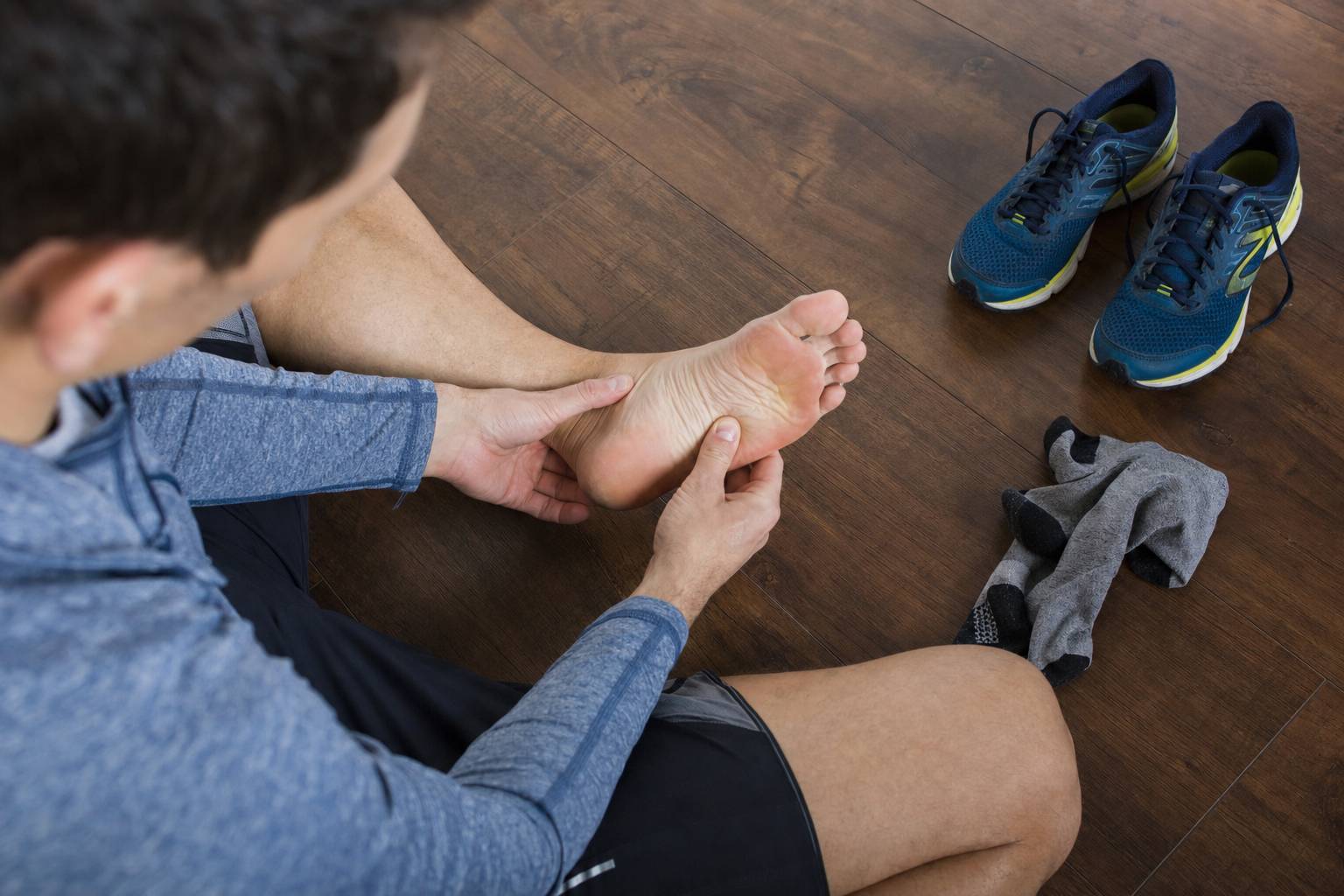 A runner examining the sole of a bare foot after a run