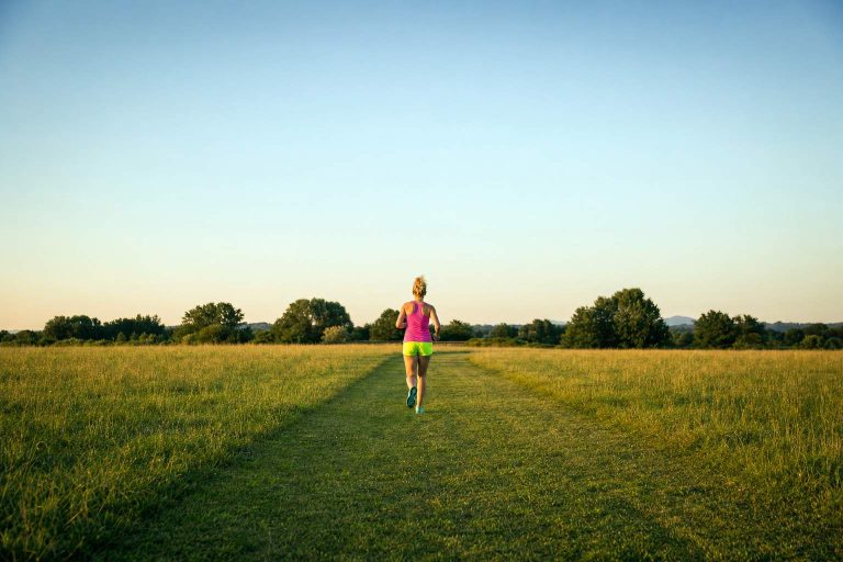 A runner finishing a short easy mile on a grass field path