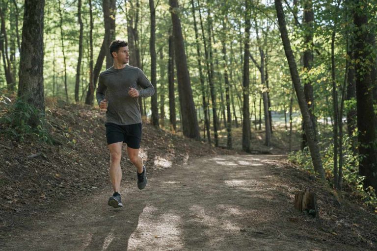 A runner on a quiet wooded path with no headphones, ears uncovered and alert to the surroundings